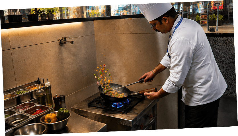 Chef tossing vegetables in a wok over a flame