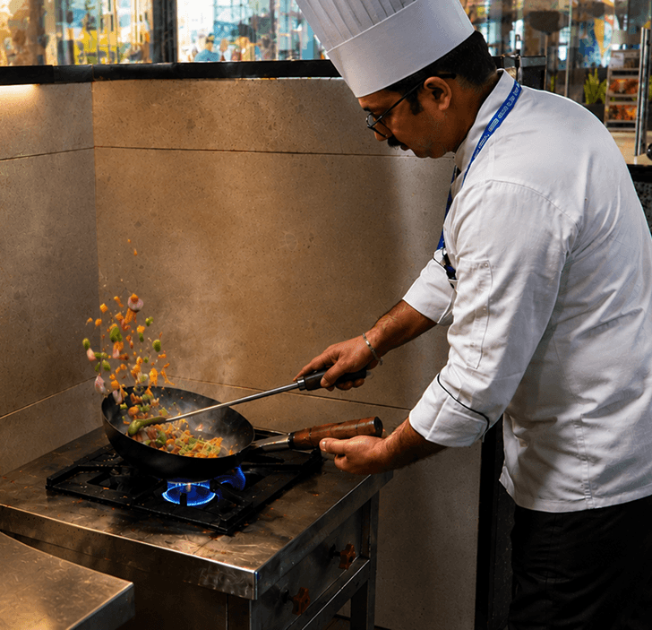 Chef tossing vegetables in a wok over a gas flame